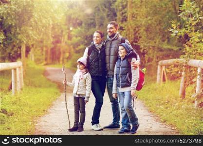 travel, tourism and hike concept - happy family walking with backpacks in woods. happy family with backpacks hiking