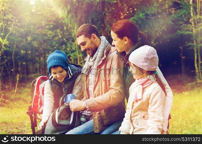 travel, tourism and hike concept - happy family with backpacks and thermos at camp. happy family with backpacks and thermos at camp