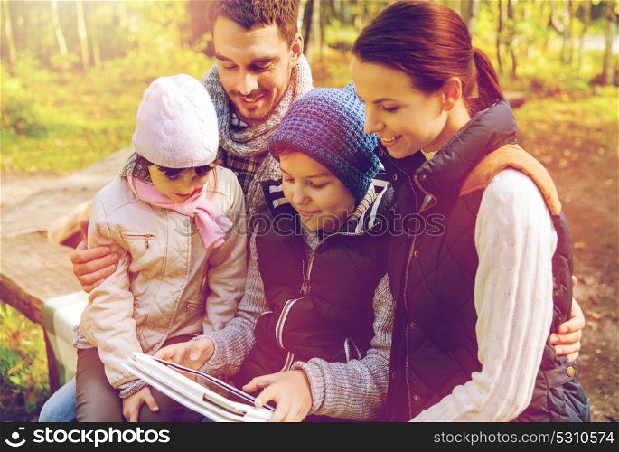travel, tourism and hike concept - happy family with tablet pc computer and backpacks at camp in woods. happy family with tablet pc and backpacks at camp