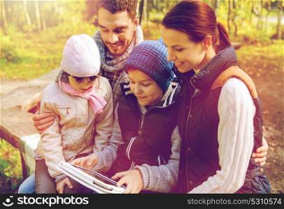 travel, tourism and hike concept - happy family with tablet pc computer and backpacks at camp in woods. happy family with tablet pc and backpacks at camp