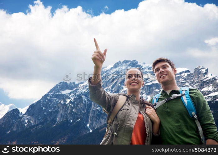 travel, tourism and hike concept - smiling couple with backpacks hiking or traveling over alps mountains background. happy couple with backpacks traveling in highlands. happy couple with backpacks traveling in highlands