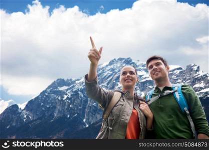 travel, tourism and hike concept - smiling couple with backpacks hiking or traveling over alps mountains background. happy couple with backpacks traveling in highlands. happy couple with backpacks traveling in highlands