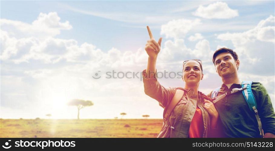 travel, tourism and hike concept - smiling couple with backpacks hiking or traveling over african savannah background. smiling couple with backpacks traveling in africa