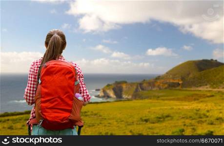 travel, tourism and hike concept - smiling young woman with backpack over big sur coast of california background. smiling woman with backpack on big sur coast. smiling woman with backpack on big sur coast