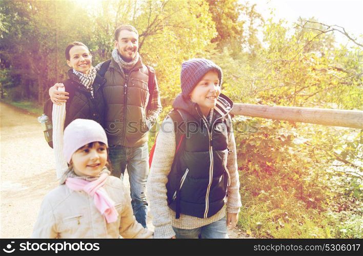 travel, tourism and hike people concept - happy family walking with backpacks outdoors. happy family with backpacks hiking
