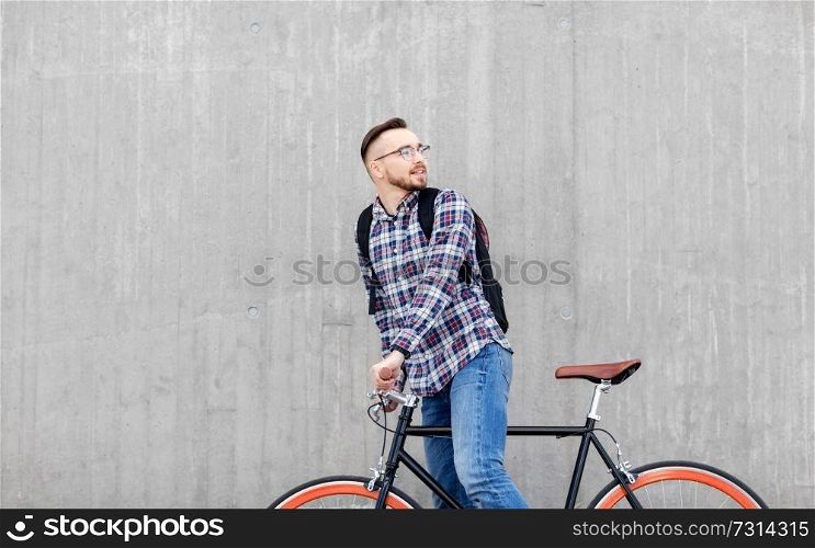 travel, tourism and lifestyle - happy young hipster man in earphones with fixed gear bike and backpack on city street. hipster man with fixed gear bike and backpack