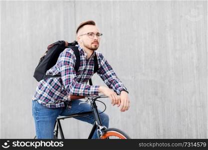 travel, tourism and lifestyle - young hipster man in earphones with fixed gear bike and backpack on city street. hipster man with fixed gear bike and backpack