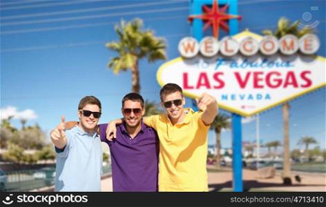 travel, tourism and male friendship concept - group of friends hugging over welcome to fabulous las vegas sign background. group of male friends hugging over las vegas sign. group of male friends hugging over las vegas sign
