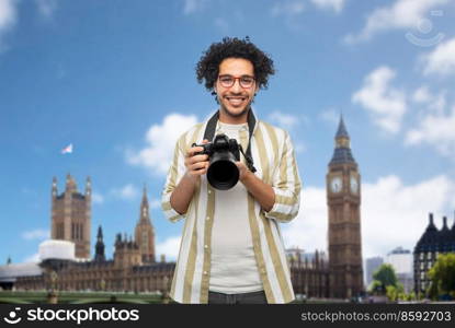 travel, tourism and people and concept - happy smiling man, photographer or tourist in glasses with digital camera over london city, england background. smiling man or photographer with camera in london