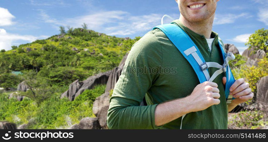 travel, tourism and people concept - close up of happy young man with backpack over exotic island hills background. close up of happy man with backpack traveling