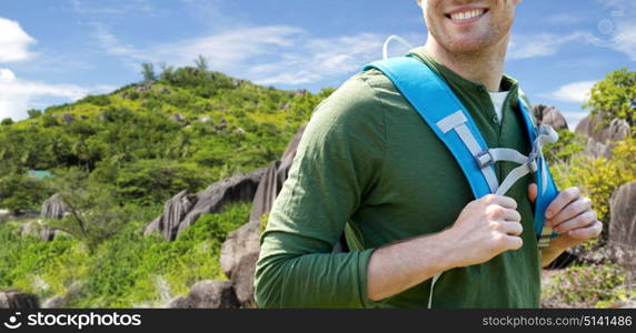 travel, tourism and people concept - close up of happy young man with backpack over exotic island hills background. close up of happy man with backpack traveling