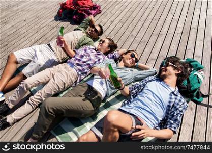 travel, tourism and people concept - friends drinking beer and cider on wooden terrace in summer. friends drinking beer and cider on wooden terrace