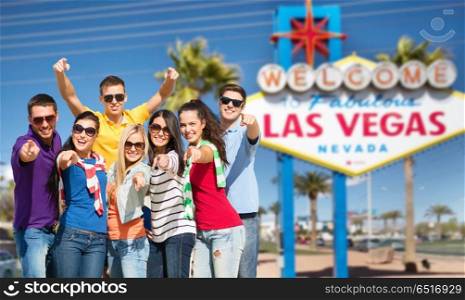 travel, tourism and people concept - group of happy friends pointing at you over welcome to fabulous las vegas sign background. happy friends pointing at you over las vegas sign. happy friends pointing at you over las vegas sign
