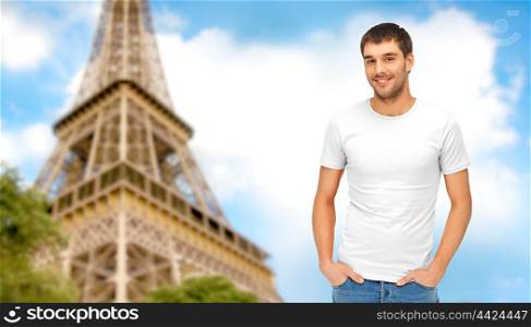 travel, tourism and people concept - handsome man in blank white t-shirt over eiffel tower and blue sky background