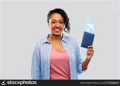 travel, tourism and people concept - happy african american young woman with passport and air ticket over grey background. african woman with passport and air ticket