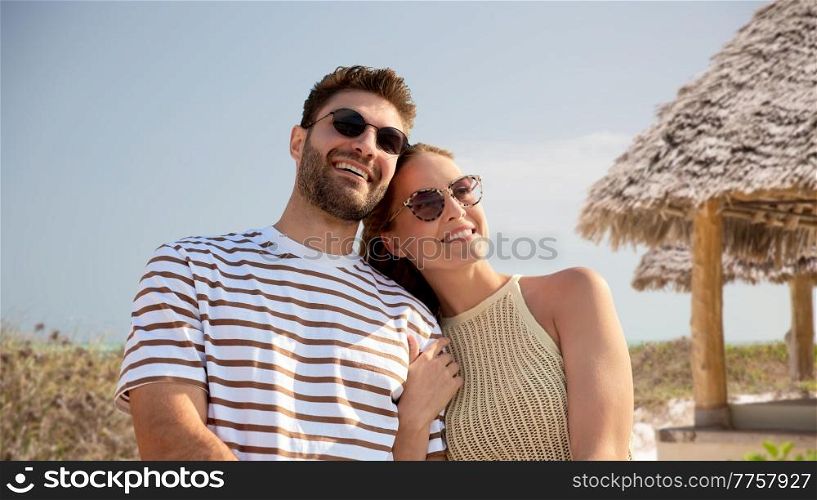 travel, tourism and people concept - happy couple in sunglasses over tropical beach background in french polynesia. happy couple on summer beach