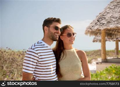 travel, tourism and people concept - happy couple in sunglasses over tropical beach background in french polynesia. happy couple on summer beach