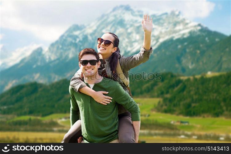 travel, tourism and people concept - happy couple in sunglasses with backpacks having fun and waving hand over mountains background. happy couple with backpacks having fun outdoors