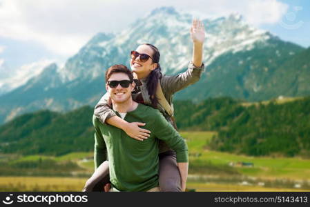 travel, tourism and people concept - happy couple in sunglasses with backpacks having fun and waving hand over mountains background. happy couple with backpacks having fun outdoors