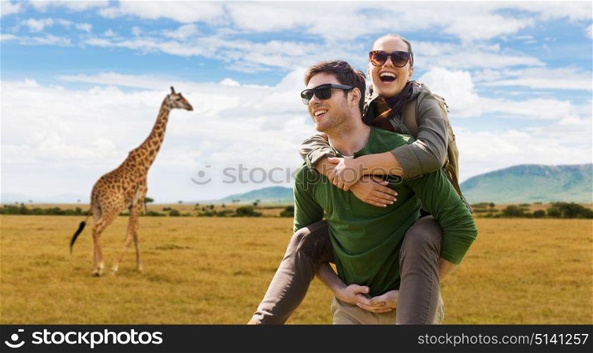 travel, tourism and people concept - happy couple with backpacks having fun over african savannah and giraffe background. smiling couple with backpacks traveling in africa
