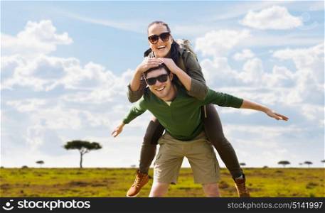 travel, tourism and people concept - happy couple with backpacks having fun over african savannah background. smiling couple with backpacks traveling in africa