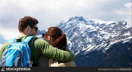 travel, tourism and people concept - happy couple with backpacks hugging over alps mountains background. happy couple with backpacks traveling. happy couple with backpacks traveling