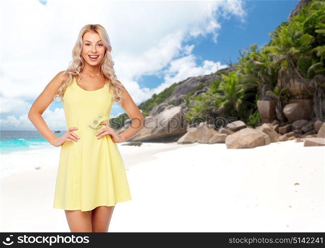 travel, tourism and people concept - happy smiling beautiful young woman in yellow dress over exotic tropical beach with palm trees background. happy young woman over exotic island beach
