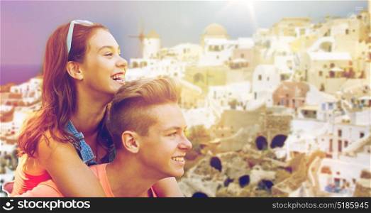 travel, tourism and people concept - happy smiling teenage couple having fun over oia town on santorini island background. happy teenage couple having fun on santorini
