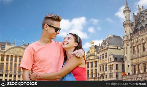 travel, tourism and people concept - happy smiling teenage couple hugging and looking at each other over grand place in brussels city background. happy teenage couple hugging in brussels city