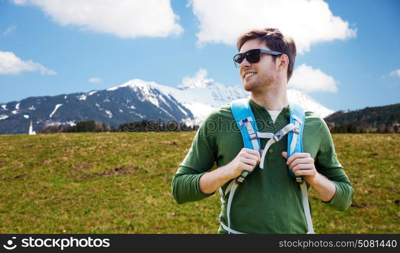 travel, tourism and people concept - happy young man in sunglasses with backpack over mountains background. happy young man with backpack traveling