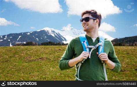 travel, tourism and people concept - happy young man in sunglasses with backpack over mountains background. happy young man with backpack traveling