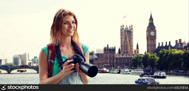 travel, tourism and people concept - happy young woman with backpack and camera photographing over london city street and big ben tower background