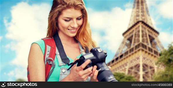 travel, tourism and people concept - happy young woman with backpack and camera photographing over eiffel tower background