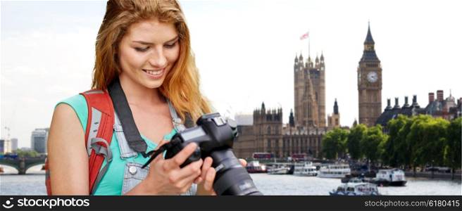 travel, tourism and people concept - happy young woman with backpack and camera photographing over london city street and big ben tower background