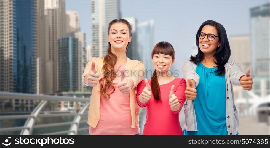 travel, tourism and people concept - international group of happy smiling different women showing thumbs up over dubai city street background. international women showing thumbs up in city