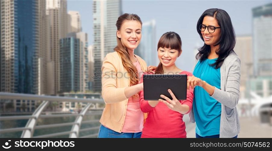 travel, tourism and people concept - international group of happy smiling different women with tablet pc computer over dubai city street background. international happy women with tablet pc in city
