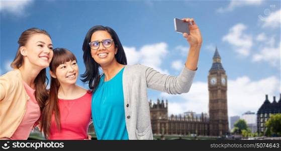 travel, tourism and people concept - international group of happy smiling different women taking selfie with smartphone over london city background. international happy women taking selfie at london