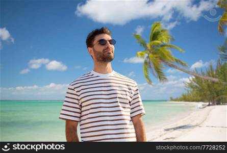 travel, tourism and people concept - portrait of young man in sunglasses over tropical beach background in french polynesia. young man in sunglasses on tropical beach