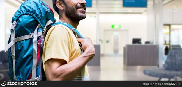 travel, tourism and people concept - smiling man with backpack over airport terminal background. man with backpack over airport terminal