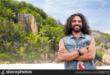 travel, tourism and people concept - smiling young hippie man in denim vest over tropical island beach background. smiling hippie man in denim vest on island beach