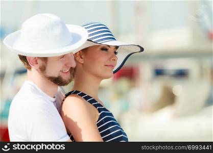 Travel tourism and people concept. Young tourist couple on vacation standing in front of boats in marina
