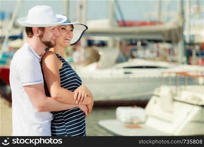 Travel tourism and people concept. Young tourist couple on vacation standing in front of boats in marina