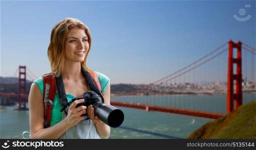 travel, tourism and photography concept - happy young woman with backpack and camera photographing over golden gate bridge in san francisco bay background. woman with backpack and camera over golden gate. woman with backpack and camera over golden gate
