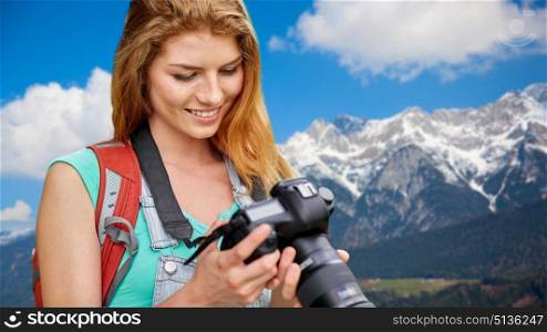 travel, tourism and photography concept - happy young woman with backpack and camera photographing over alps mountains background. woman with backpack and camera over alps mountains. woman with backpack and camera over alps mountains