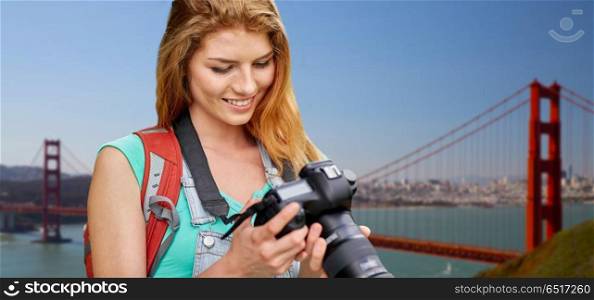 travel, tourism and photography concept - happy young woman with backpack and camera photographing over golden gate bridge in san francisco bay background. woman with backpack and camera over golden gate. woman with backpack and camera over golden gate