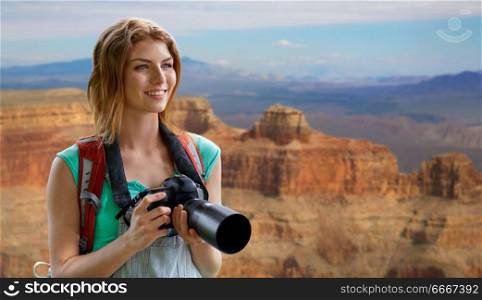 travel, tourism and photography concept - happy young woman with backpack and camera photographing over grand canyon national park background. woman with backpack and camera at grand canyon. woman with backpack and camera at grand canyon
