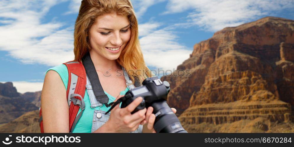 travel, tourism and photography concept - happy young woman with backpack and camera photographing over grand canyon national park background. woman with backpack and camera at grand canyon. woman with backpack and camera at grand canyon