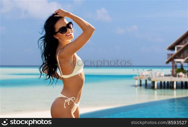 travel, tourism and summer concept - happy smiling young woman in bikini swimsuit posing over tropical beach background in french polynesia. smiling young woman in bikini swimsuit on beach