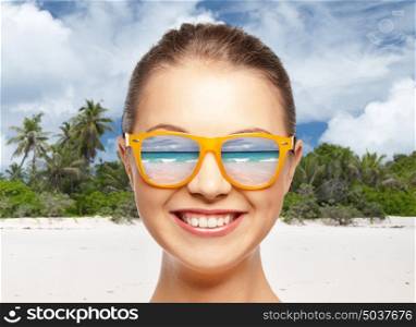travel, tourism and summer holidays concept - face of happy smiling teenage girl in shades over exotic tropical beach background. happy smiling teenage girl in shades over beach