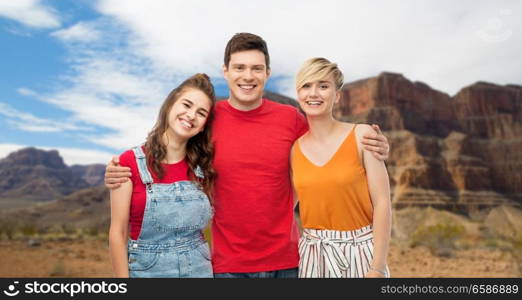 travel, tourism and summer holidays concept - group of happy smiling friends hugging over grand canyon national park background. happy friends hugging